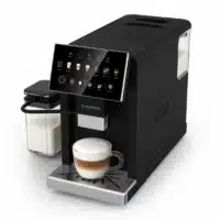 Dyceros La machine à café Dyceros Setosa Latte 15 bars superautomatique avec écran tactile prépare le cappuccino dans une tasse en verre, en utilisant son réservoir de lait connecté, tout en reposant sur un plateau d'égouttage argenté.